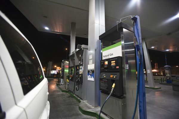 نمای نزدیک از ماشین بریده شده در پمپ بنزین با نمای پمپ سوخت و گاز طبیعی در شب