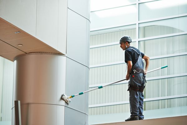 کارگر نظافتچی زن در تمیز کردن یکنواخت پنجره های داخلی ساختمان تجاری