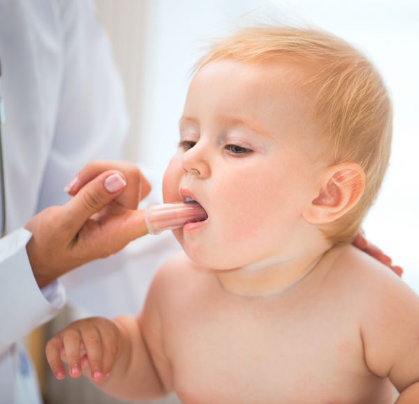 دکتر دهان کودک را با یک برس مخصوص تمیز می کند