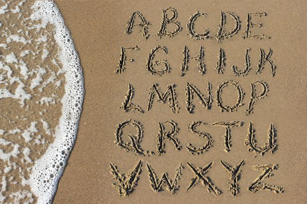 حروف الفبای دست نوشته در شن و ماسه در ساحل