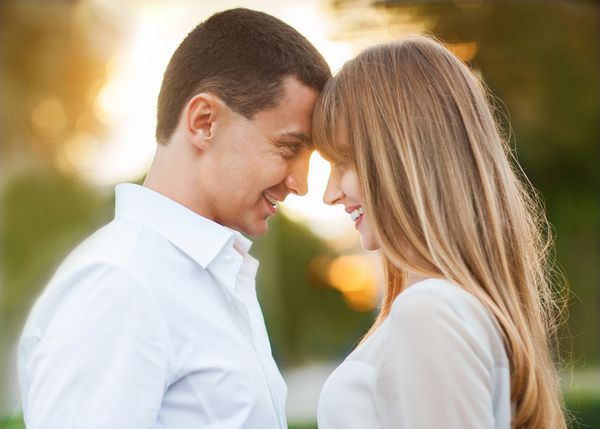 زوج جوان عاشق در فضای باز آنها لبخند می زنند و به یکدیگر نگاه می کنند
