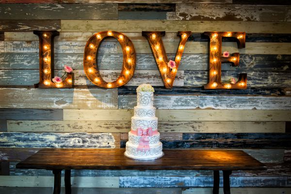 تصویر کیک عروسی با کلمه عشق به عنوان علامت روی پس زمینه روستایی