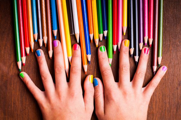 مداد رنگین کمانی رنگی و دستان نوجوان با ناخن های رنگارنگ