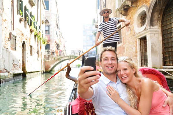 زن و شوهر در ونیز در حال گوندو سواری عاشقانه در قایق در تعطیلات تعطیلات سفر با هم خوشحال هستند زوج زیبای جوان عاشقانه در حال گرفتن عکس از خود در حال قایقرانی در کانال ونیزی در گوندولا ایتالیا