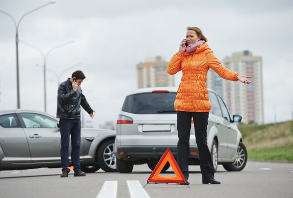 برخورد ماشین راننده زن و مرد در حال بررسی خودروهای آسیب دیده پس از تصادف در شهر