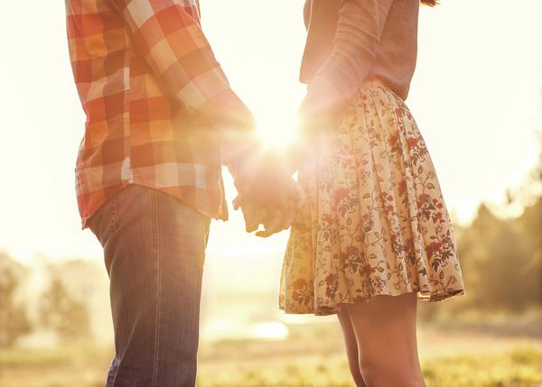زوج جوان عاشق قدم زدن در پارک پاییزی دست در دست هم به غروب آفتاب نگاه می کنند