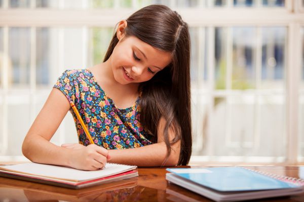 دختر کوچک زیبا از یادگیری و انجام تکالیف لذت می برد
