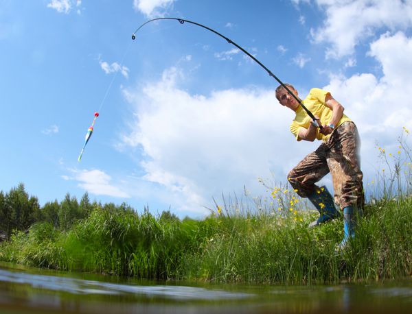 مرد جوانی که در یک روز آفتابی در یک برکه ماهیگیری می کند