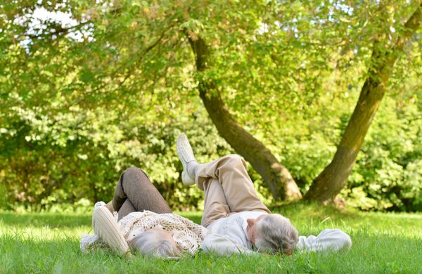 زوج سالمند شادی که در پارک پاییز دراز کشیده اند