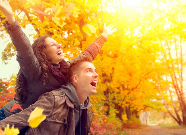 زوج خوشبخت در پارک پاییز سقوط خانواده جوان در حال تفریح در فضای باز درختان و برگ های زرد رنگ مرد و زن خندان بیرون مفهوم آزادی
