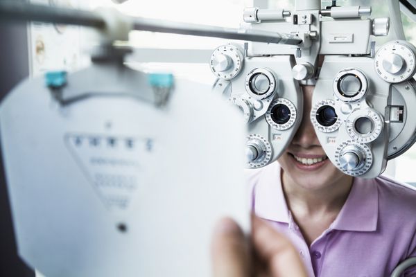 نمای نزدیک اپتومتریست در حال انجام معاینه چشم بر روی زن جوان