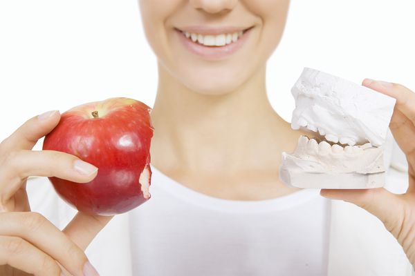 زنی که نمونه دندان و سیب در دست دارد