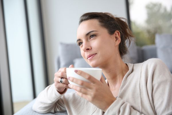 زن شرم آور در حال استراحت در خانه با فنجان چای