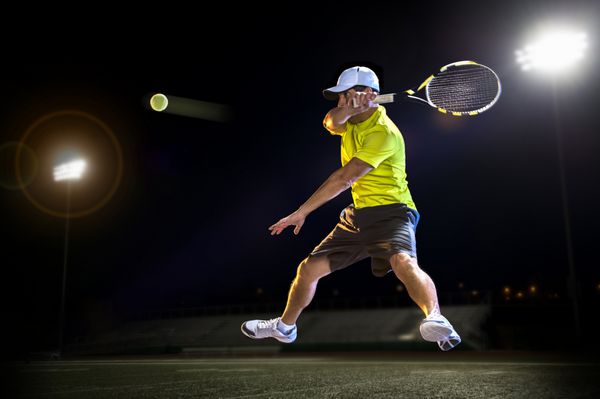 ضربه زدن بازیکن تنیس به توپ در شب