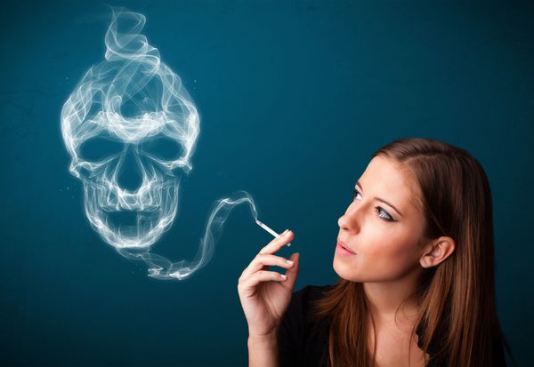 زن جوان زیبا در حال کشیدن سیگار خطرناک با دود سمی جمجمه
