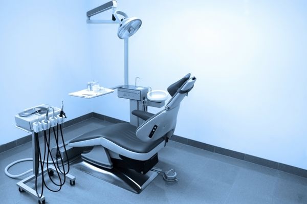 فضای داخلی کلینیک دندانپزشکی با صندلی دندانپزشکی ابزار دندانپزشکی و تجهیزات نورپردازی دندان تون آبی
