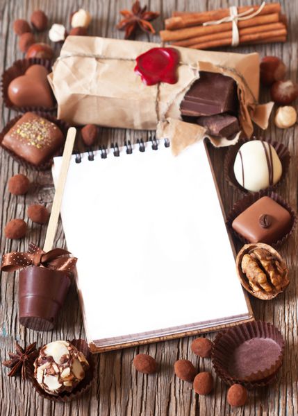 قاب شکلات و ادویه جات با دفترچه یادداشت برای متن روی پس زمینه چوبی