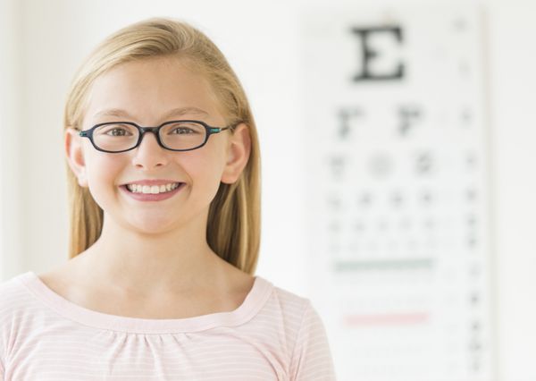 پرتره دختر شادی که عینک به چشم دارد در کلینیک