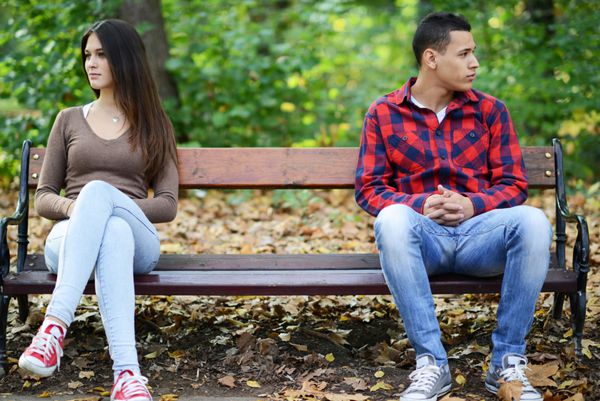 زن و شوهر جوان در حال نزاع و نشستن روی نیمکت در پارک