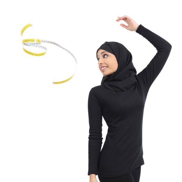 زن تناسب اندام عرب سعودی در حال پرتاب نوار پیمانه جدا شده روی پس زمینه سفید