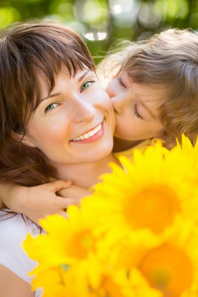 زن و کودک با دسته گل در پس زمینه سبز مفهوم تعطیلات خانوادگی بهاری روز مادر