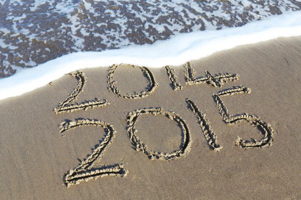 مفهوم سال جدید 2015 در راه است - کتیبه 2014 و 2015 روی شن و ماسه ساحل موج شروع به پوشاندن ارقام 2014 می کند