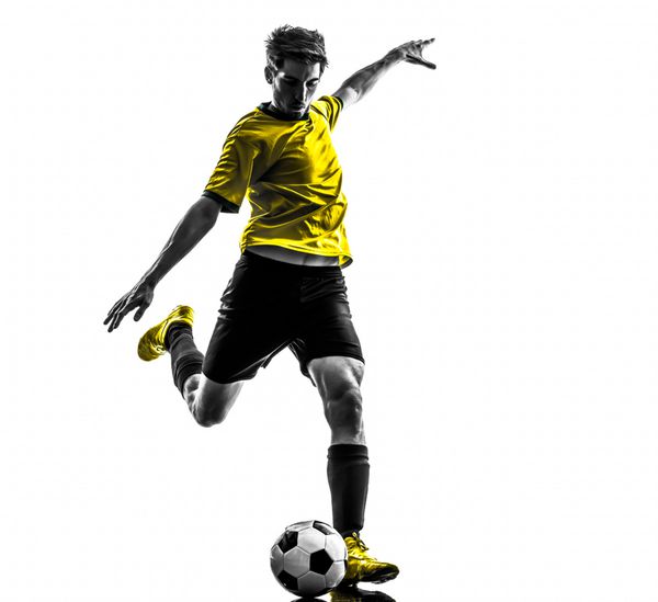 یک مرد جوان فوتبالیست برزیلی در حال لگد زدن در استودیو silhouette در زمینه سفید