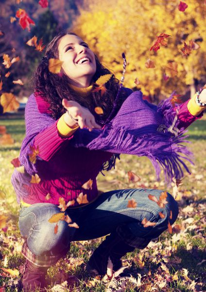 دختری در حال لذت بردن از اوقات فراغت در یک پارک در یک روز پاییزی