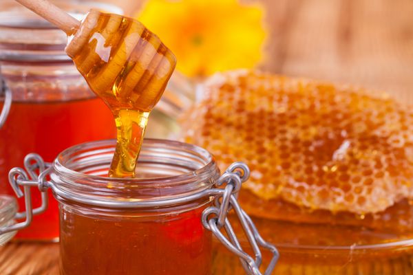 عسل در شیشه با لانه زنبوری و آب ریز چوبی