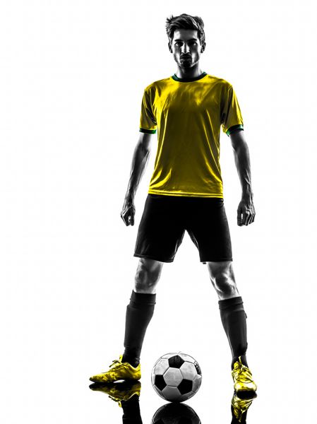 یک مرد جوان فوتبالیست برزیلی در استودیوی silhouette در پس زمینه سفید ایستاده است