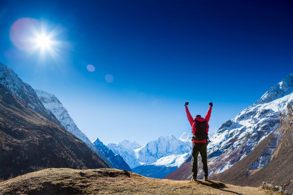 مفهوم موفقیت برنده کوهنوردی که پس از پیاده‌روی به قله بالای کوه بالای ابرها با دست‌های برافراشته در آسمان خوشحال و شادمان می‌گوید
