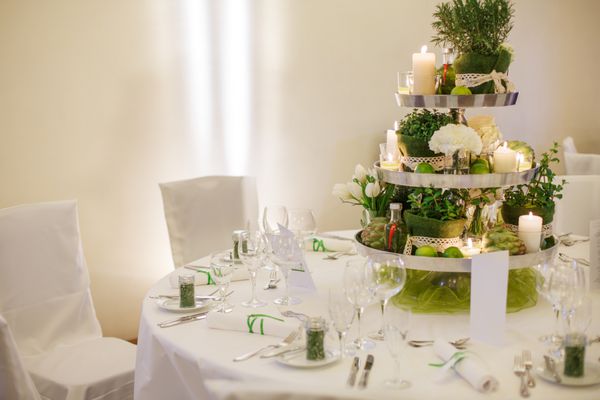 چیدمان میز زیبا برای جشن عروسی یا جشن سبز رنگ داخل خانه با چیدمان گل و شمع بزرگ
