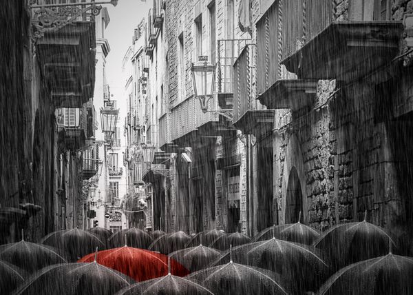عکس سیاه و سفید تعداد زیادی چتر به همین سبک در خیابانی بارانی در سلونا تصویر تون شده است یک چتر قرمز است