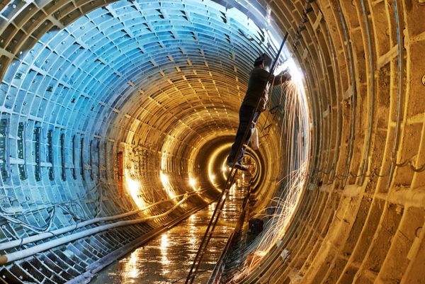 جوشکار تونلر که با الکترود در جوشکاری قوس الکتریکی در محل ساخت و ساز مترو زیرزمینی کار می کند