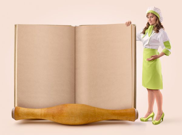 دختر آشپز صفحه ای از یک کتاب قدیمی را در زمینه بژ نشان می دهد