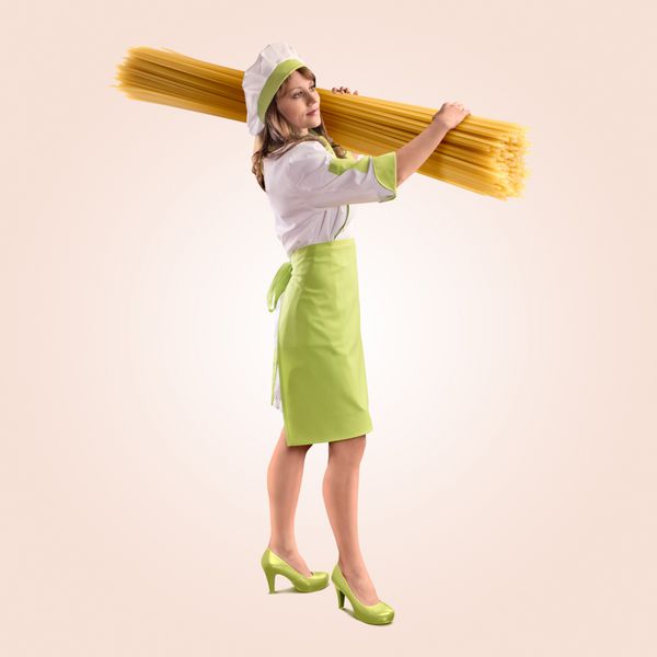 دختر آشپز با اسپاگتی بزرگ خوشمزه در پس زمینه بژ