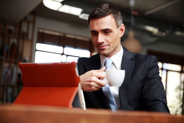 تاجر در حال نوشیدن قهوه و خواندن اخبار در کافه