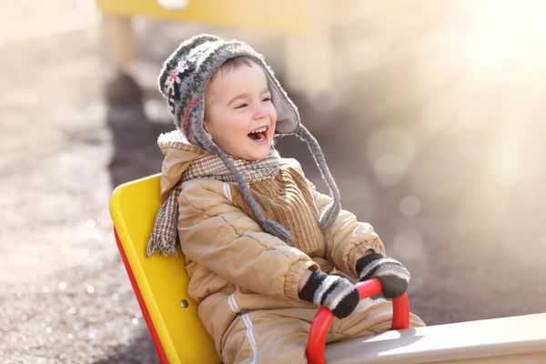 کودک شاد در یک تاب در یک روز آفتابی بهاری