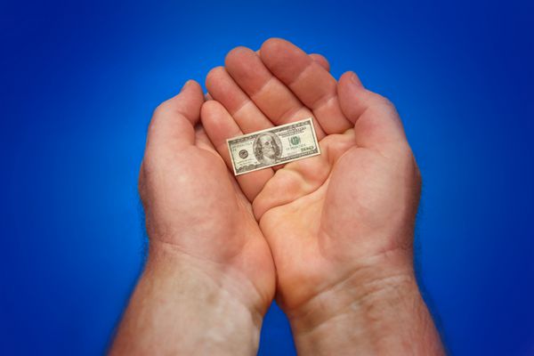 تصویر تورم - دست هایی که آخرین اسکناس کوچک دلار ما را در دست دارند پس زمینه آبی