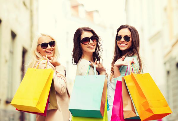 مفهوم خرید و گردشگری - دختران زیبا با کیف های خرید در ctiy