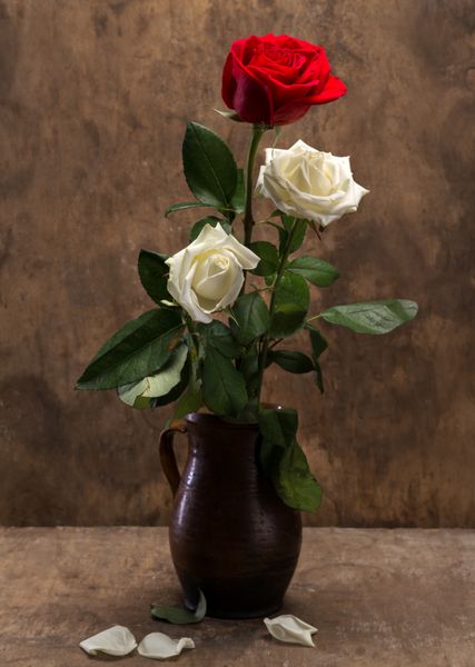 گل رز در یک گلدان روی زمینه چوبی