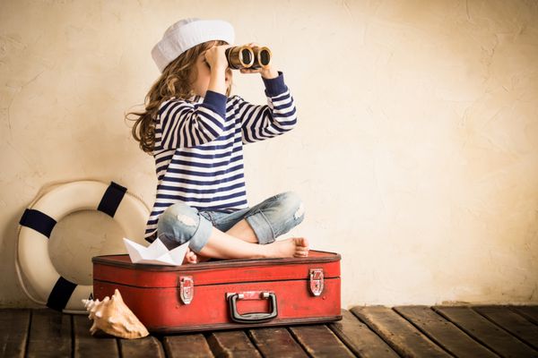 بچه شاد با قایق بادبانی اسباب بازی در داخل خانه مفهوم سفر و ماجراجویی کودک تابستان تعطیلات