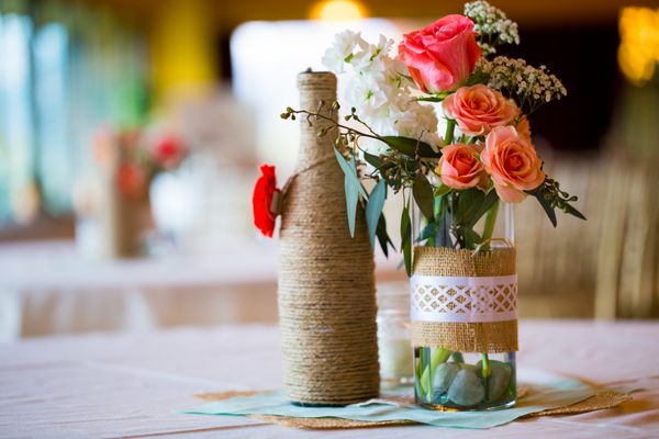 دکورهای دکور عروسی وسط میز عروسی با بطری‌های پیچیده شده در کرفس و گل‌های رز