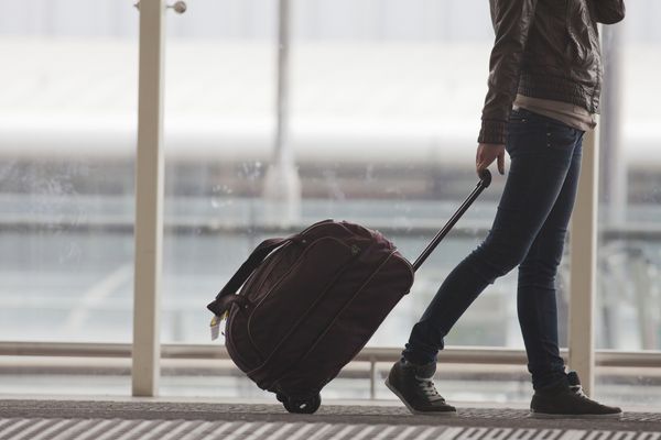زن چمدان شما را در ترمینال فرودگاه هنگ کنگ حمل می کند