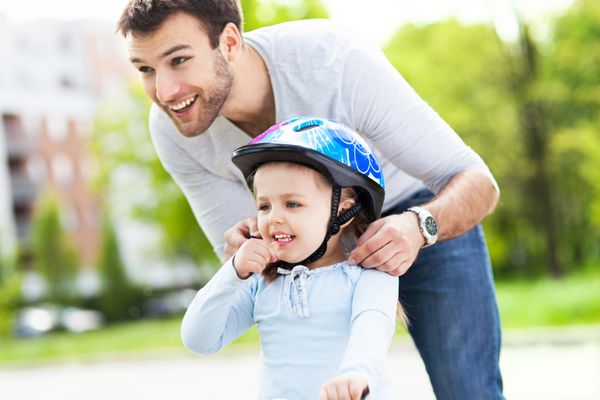 کمک پدر به دختر با کلاه ایمنی دوچرخه