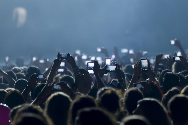 تسالونیکی یونان 8 مه 2014 افرادی که در طول یک کنسرت موسیقی زنده روی صحنه برای تور قلب در سالن ورزشی در تسالونیکی با تلفن هوشمند لمسی عکس می گیرند
