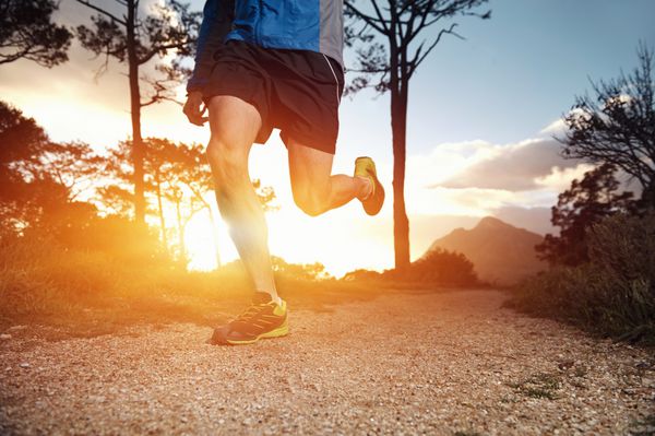 مرد تریل دونده در حال ورزش برای تناسب اندام در طلوع آفتاب در کوهستان در حال انجام ورزش