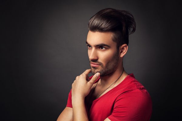 مرد جوان با مدل موی مدرن که با پیراهن قرمز در استودیو ژست گرفته است