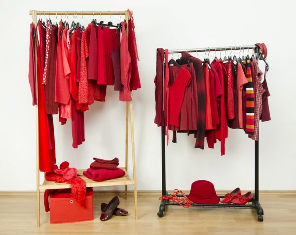 کمد لباس با لباس های قرمز آویزان روی یک قفسه به خوبی چیده شده است لباس های قرمز روی چوب لباسی و لوازم جانبی در اتاق رختکن