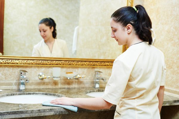 سرویس ال کارگر زن خانه دار تمیز کردن میز از گرد و غبار در حمام